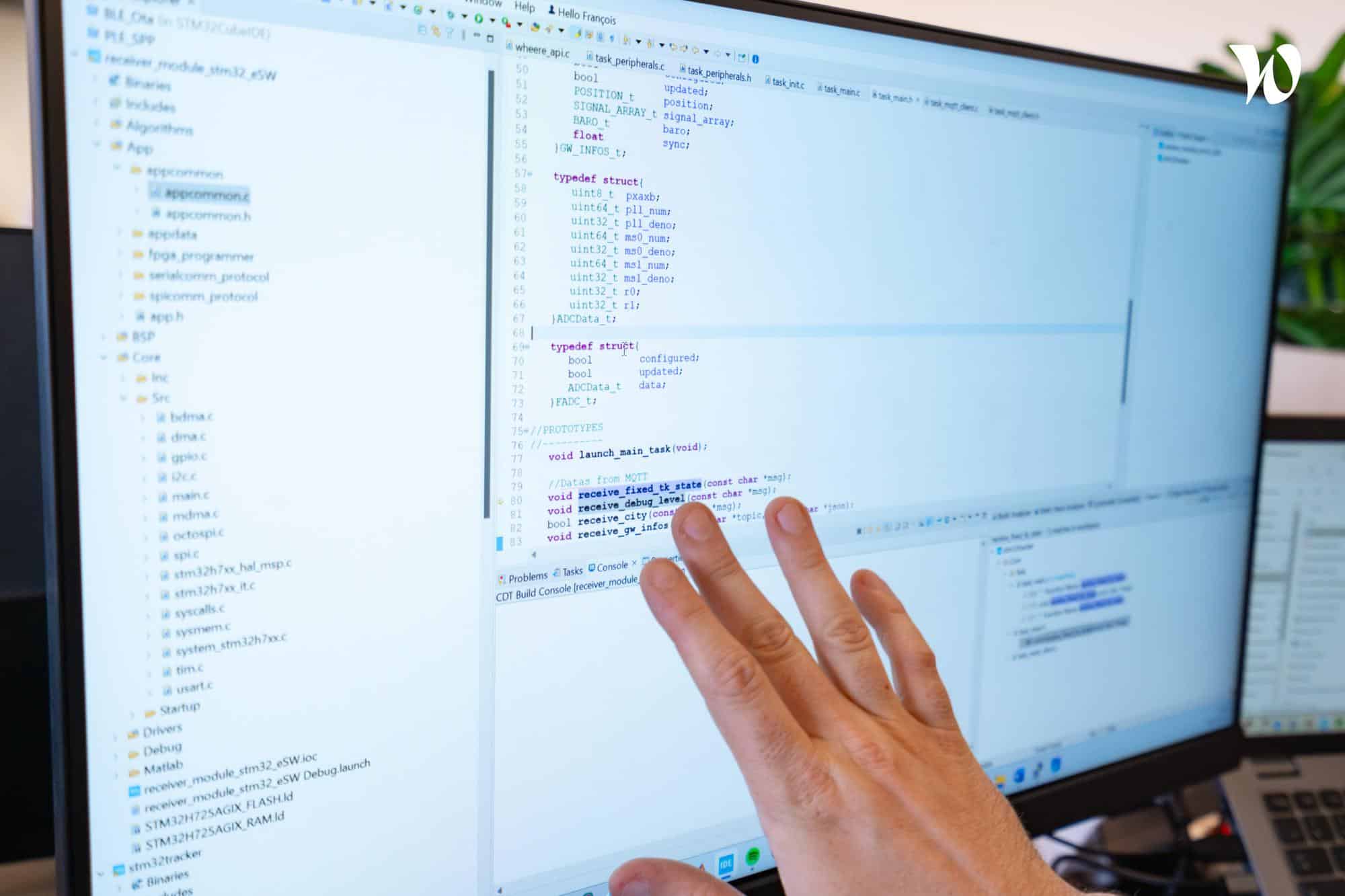 Ecran d'ordinateur qui affiche des lignes de code avec une main posée dessus et qui illustre la technologie de géolocalisation indoor Wheere