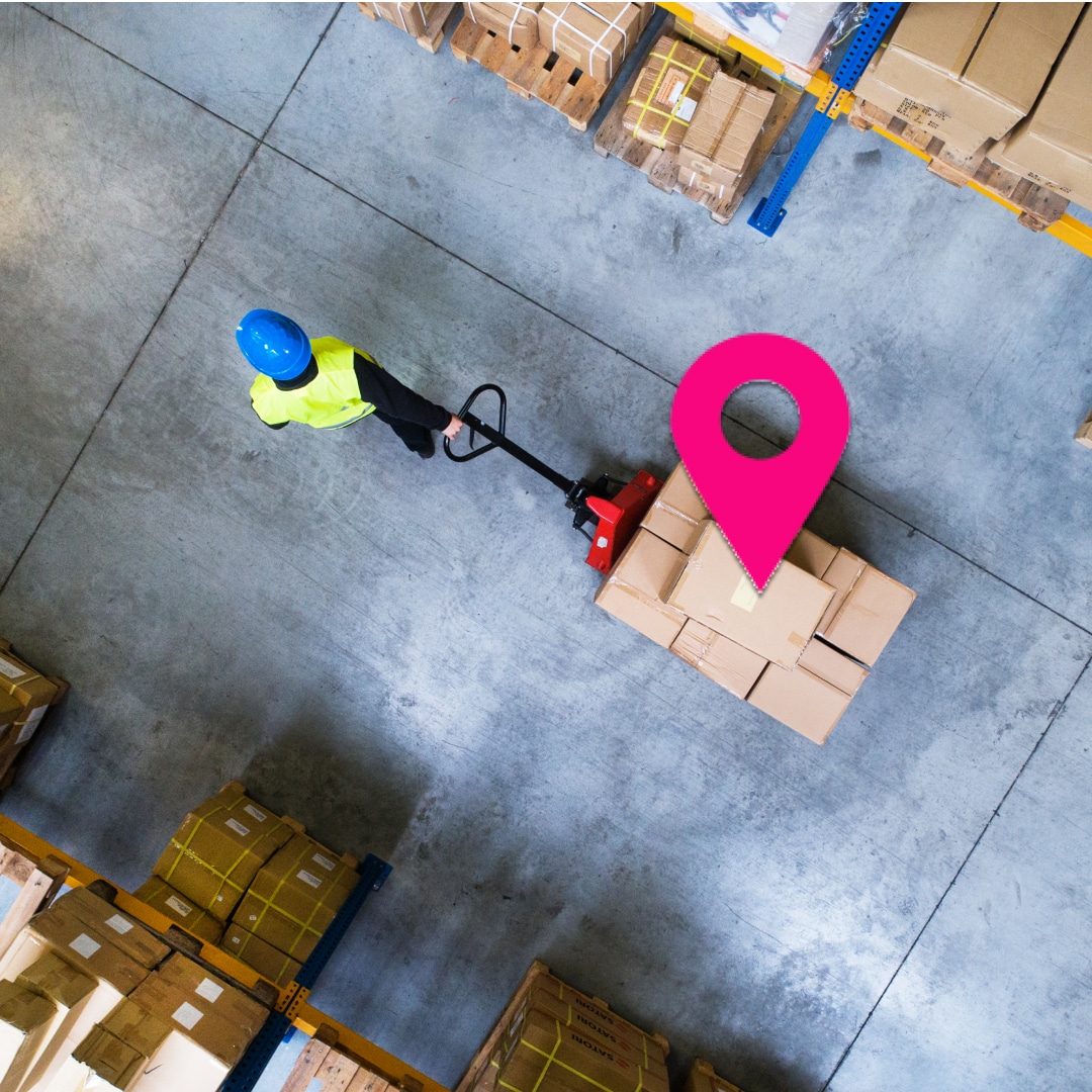 Vue aérienne d’un opérateur logistique déplaçant une palette dans un entrepôt, illustrant les enjeux métier pour choisir un système de géolocalisation indoor adapté.