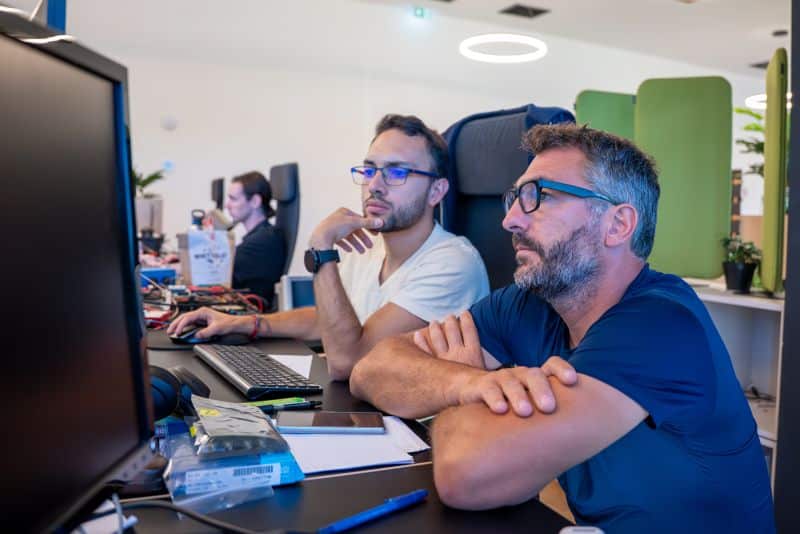 Pierre-Arnaud Coquelin analyse des données avec Daniel, son collaborateur chez Wheere, illustrant une approche du leadership humain à l'image de son personal branding.